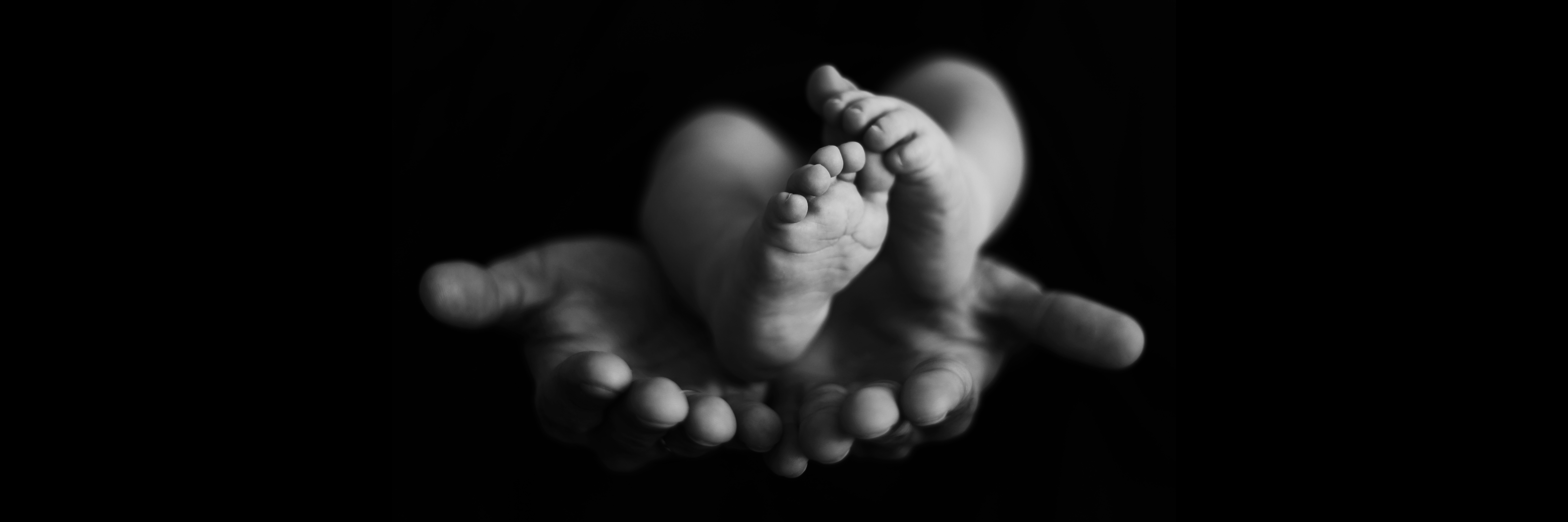 Baby feet held by parents